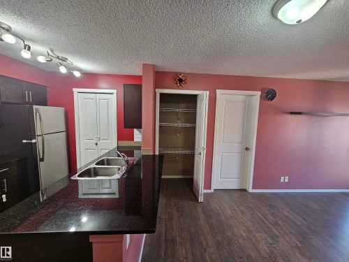 Kitchen featuring dark cabinetry, a double basin stainless steel sink, dark countertops, and stainless steel appliances - #421 5816 Mullen Place Nw, Edmonton, AB 