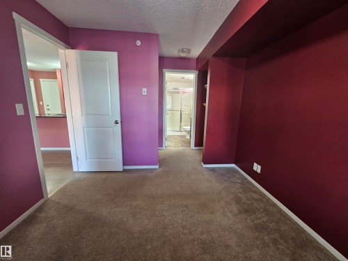 Plush carpeting, two-panel interior doors, and a built-in shelving unit - #421 5816 Mullen Place Nw, Edmonton, AB 