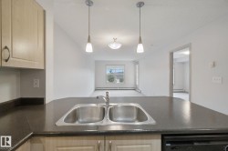 Kitchen island with dual basin stainless steel sink, dark countertop, and pendant lighting - 