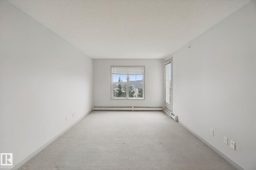 Carpeted room with a window, vertical blinds, and a glass-paneled door - #406 11449 Ellerslie Rd Sw, Edmonton, AB 