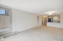 Open-concept living space featuring a kitchen with light wood-finish cabinetry, black appliances, and pendant lighting - 