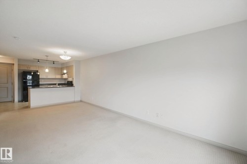 Open-concept living space featuring carpet flooring and neutral wall tones - #406 11449 Ellerslie Rd Sw, Edmonton, AB 