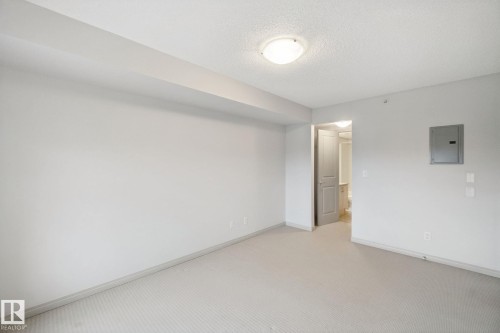 Neutral-toned carpeting, white painted walls, and a flush mount ceiling light fixture - #406 11449 Ellerslie Rd Sw, Edmonton, AB 
