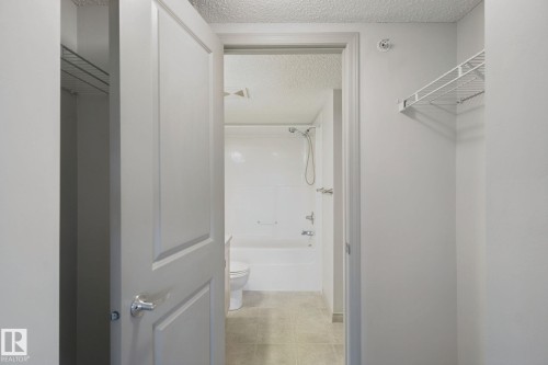 Recessed lighting, tile flooring, built-in wire shelving, white paneled doors, and a full bathtub with a shower - #406 11449 Ellerslie Rd Sw, Edmonton, AB 