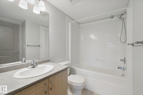 Vanity with a laminate countertop and integrated sink, chrome faucet, and wood-finish cabinetry - #406 11449 Ellerslie Rd Sw, Edmonton, AB 