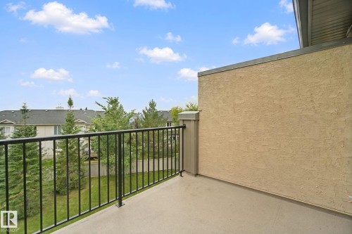 Outdoor balcony featuring concrete flooring, black metal railings, and a stucco exterior wall - #406 11449 Ellerslie Rd Sw, Edmonton, AB 
