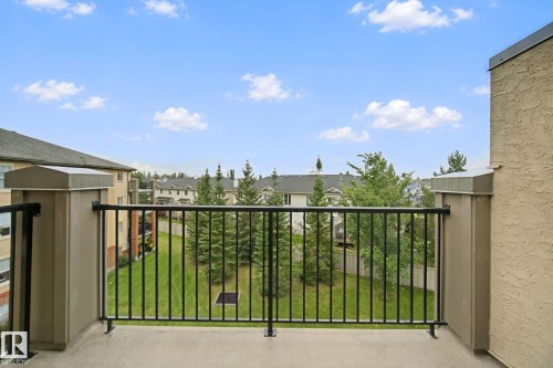 Balcony with a concrete surface, black metal railings, and stucco exterior walls - #406 11449 Ellerslie Rd Sw, Edmonton, AB 