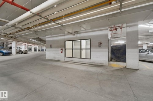 Underground parking garage featuring concrete flooring, exposed ceiling piping, and fluorescent lighting - #406 11449 Ellerslie Rd Sw, Edmonton, AB 