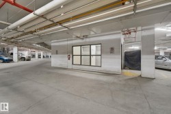 Underground parking garage featuring concrete flooring, exposed ceiling piping, and fluorescent lighting - 