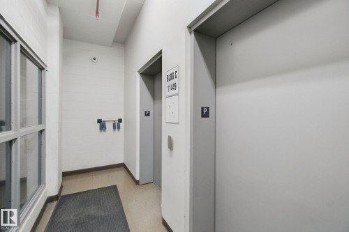 Elevator access within the building, featuring block wall construction and industrial-style window framing - #406 11449 Ellerslie Rd Sw, Edmonton, AB 