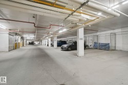 Underground parking facility featuring concrete flooring, overhead lighting, and dedicated storage units - 