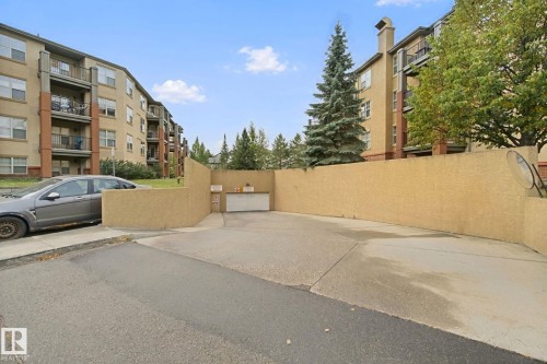 Concrete driveway with a stucco privacy wall - #406 11449 Ellerslie Rd Sw, Edmonton, AB 