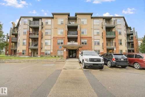 Multi-story building featuring a brick and stucco exterior, multiple private balconies, and a designated parking area - #406 11449 Ellerslie Rd Sw, Edmonton, AB 