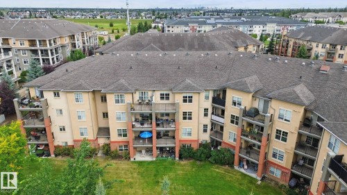 Multi-story building featuring private balconies, a pitched shingle roof, and a beige and brick facade - #406 11449 Ellerslie Rd Sw, Edmonton, AB 