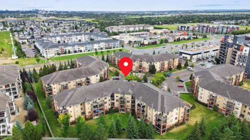 Low-rise residential buildings surrounded by green spaces, featuring private balconies and surface parking areas - #406 11449 Ellerslie Rd Sw, Edmonton, AB 