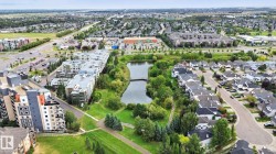 Expansive neighborhood featuring a large pond, extensive green spaces, and a variety of residential buildings including multi-story complexes and single-family homes - 