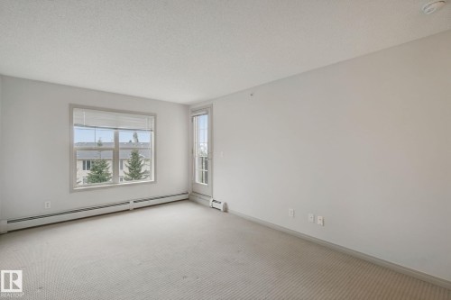 Neutral color palette, window with horizontal blinds, glass panel door, wall-to-wall carpeting, and baseboard heating - #406 11449 Ellerslie Rd Sw, Edmonton, AB 