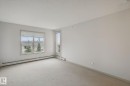 Neutral color palette, window with horizontal blinds, glass panel door, wall-to-wall carpeting, and baseboard heating - #406 11449 Ellerslie Rd Sw, Edmonton, AB 