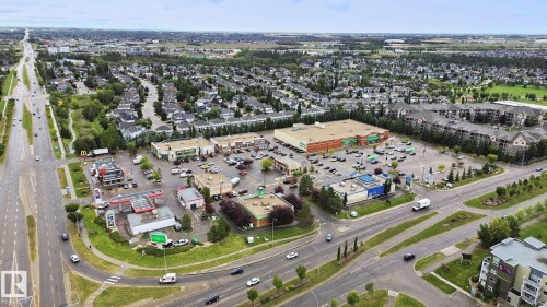 Aerial perspective displaying a commercial property with multiple buildings, surface parking, and direct access to a multi-lane road - #406 11449 Ellerslie Rd Sw, Edmonton, AB 