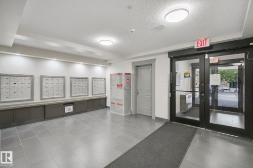 Building entrance featuring full-light glass doors, recessed lighting, and a mailroom with individual mailboxes - #406 11449 Ellerslie Rd Sw, Edmonton, AB 