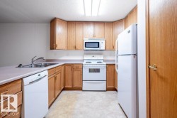 Kitchen featuring light wood cabinetry, white appliances, a double basin stainless steel sink, and light-toned countertops - 