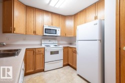 Kitchen featuring wood cabinetry, laminate countertops, a stainless steel sink, and white appliances - 