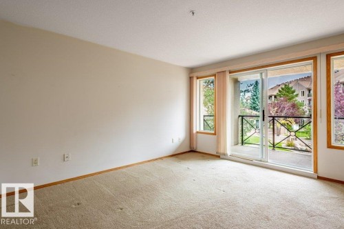 Room for lots of furniture in this large living room with patio doors opening to a balcony with black metal railing OVERLOOKING THE POND - #203 8912 156 St Nw, Edmonton, AB 