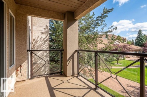 Spacious balcony featuring a glass and metal railing, and view of the pond and gardens - #203 8912 156 St Nw, Edmonton, AB 