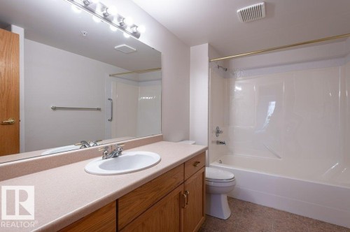 This spacious, primary bath features a tub/shower, large vanity & mirror, toilet & linen storage. - #203 8912 156 St Nw, Edmonton, AB 