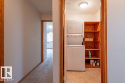 Insuite laundry with stackable washer/dryer, large storage shelf and door to close off the space. - #203 8912 156 St Nw, Edmonton, AB 
