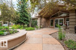 Entryway featuring stone-clad columns, a gabled roofline, and large fixed windows - 