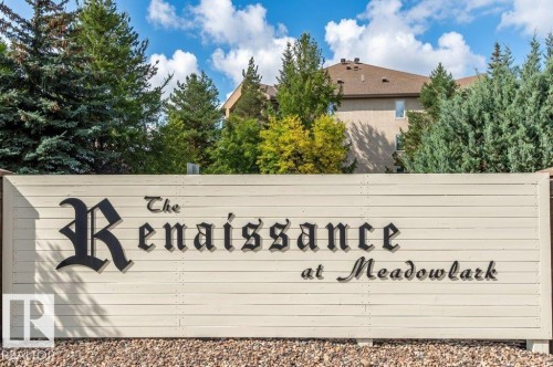 Community entrance sign for The Renaissance at Meadowlark, featuring mature trees and a residential buildings in the background - #203 8912 156 St Nw, Edmonton, AB 