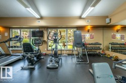 Dedicated fitness space featuring rubberized flooring, mirrored wall, recessed lighting, and expansive windows - 