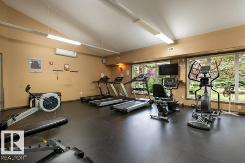 Fitness area featuring durable flooring, large picture windows, and integrated wall-mounted television - #203 8912 156 St Nw, Edmonton, AB 