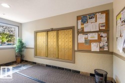 Recessed ceiling lighting illuminates the entry area, featuring a multi-pane window, brass-finish mailboxes, and cork bulletin boards - 