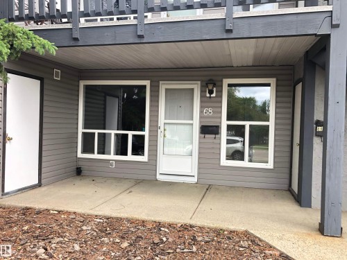 Grey siding exterior with white trim windows and a covered concrete patio - #68 1503 Mill Woods Rd E Nw, Edmonton, AB 