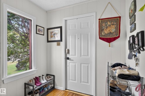 White paneled walls, wood-finish flooring, and a paneled entry door - 12309 80 Street Nw, Edmonton, AB 