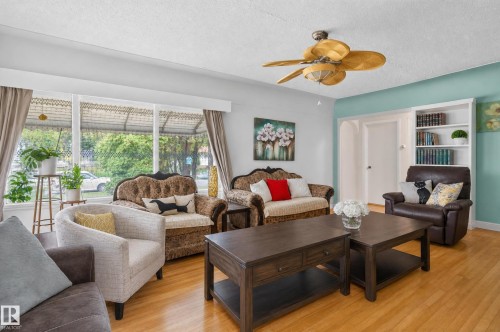 Living area with wood-finish flooring, a large picture window, a ceiling fan, and built-in shelving - 12309 80 Street Nw, Edmonton, AB 