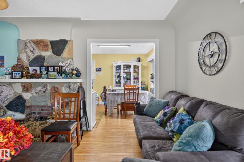 Stone fireplace with a hearth, wood-finish flooring, and a large cased opening - 12309 80 Street Nw, Edmonton, AB 