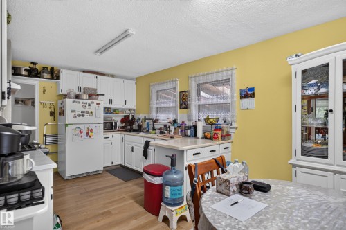 Kitchen featuring white cabinetry, light countertops, wood-finish flooring, and dual windows - 12309 80 Street Nw, Edmonton, AB 