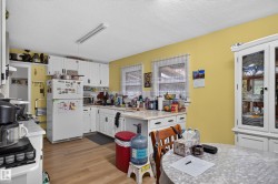 Kitchen featuring white cabinetry, light countertops, wood-finish flooring, and dual windows - 