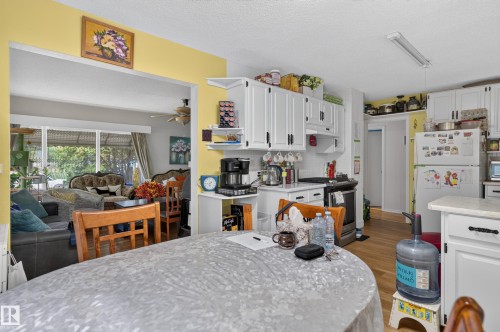 Kitchen featuring white cabinetry, subway tile backsplash, and wood-finish flooring - 12309 80 Street Nw, Edmonton, AB 