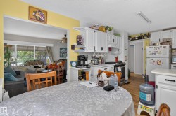 Kitchen featuring white cabinetry, subway tile backsplash, and wood-finish flooring - 