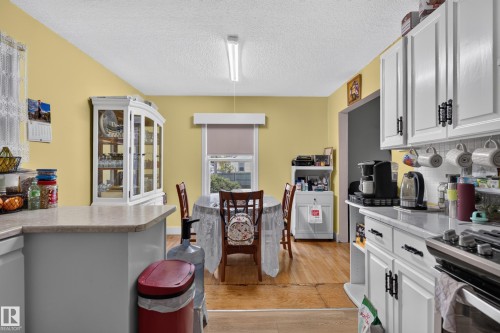 Well-appointed kitchen featuring white cabinetry with black hardware, light-colored countertops, and hardwood-finish flooring - 12309 80 Street Nw, Edmonton, AB 