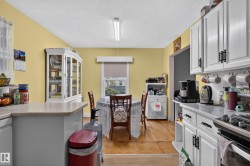 Well-appointed kitchen featuring white cabinetry with black hardware, light-colored countertops, and hardwood-finish flooring - 