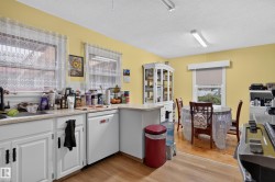 Kitchen featuring wood-finish flooring, white cabinetry, a built-in dishwasher, and ample counter space - 