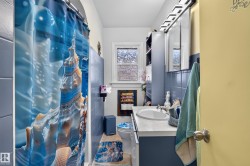 Full bathroom featuring a single vanity with an integrated sink, blue tile wainscoting, and a window with privacy glass - 
