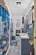 Compact bathroom with a shower-tub combination, a single vanity with a white countertop, and a window with frosted glass - 