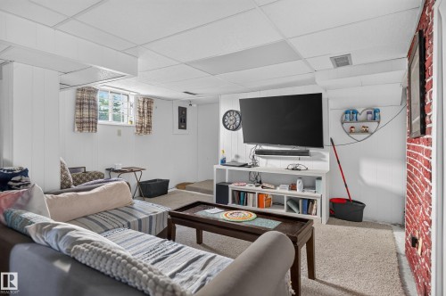 Paneled walls, drop ceiling, carpeted flooring, built-in shelving, and exposed brick-finish wall - 12309 80 Street Nw, Edmonton, AB 