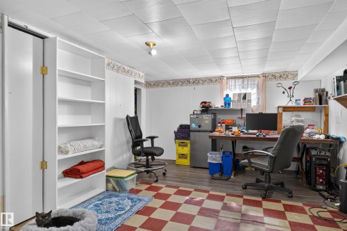 Built-in white shelving, drop ceiling, wood-finish flooring, and a checkered floor section - 12309 80 Street Nw, Edmonton, AB 